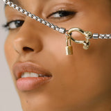 The Herradura Lock Single Necklace, a bold silver chain necklace featuring a statement gold clasp and lock pendant. This mixed-metal piece combines modern elegance with an edgy touch, perfect for adding sophistication to any outfit.