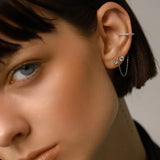 The Ear Cuff with Chain Set, which is a four-pieceThe Ear Cuff with Chain Set, which is a four-piece silver earring set, features a sparkling ear cuff connected by a delicate chain to a stud, accompanied by two additional solitaire studs for versatile styling options and an elegant, contemporary look.