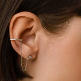 Model wearing The Ear Cuff with Chain Earring which features a hoop cuff with shimmering diamonds and a dainty chain connected to a pear-shaped diamond earring.