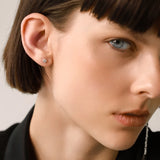 The SINGLE MINI STUD EARRING, which is a delicate silver earring featuring a single shimmering stone encircled by a polished design, perfect for adding subtle elegance to everyday or formal looks.