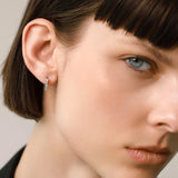 The Prong Hoops, which are a pair of dainty gold hoop earrings, feature sparkling prong-set crystals that add a touch of elegance and subtle shine. These versatile earrings are perfect for everyday wear or layering with other pieces to create a sophisticated, modern look. ||| GOLD