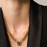 Model wearing the Emerald Dot Necklace Set, a two-piece gold necklace featuring a delicate chain with a single emerald pendant and a matching choker chain.