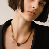 Model wearing the Emerald Dot Necklace Set, a two-piece gold necklace featuring a delicate chain with a single emerald pendant and a matching choker chain.