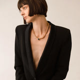 Model wearing the Emerald Dot Necklace Set, a two-piece gold necklace featuring a delicate chain with a single emerald pendant and a matching choker chain.