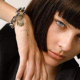 Model wearing the CARABINER SQUARE PUERTO BRACELET made of silver chunky square link chain with silver carabiner with the dalmatian charm nd spike link charms. ||| SILVER