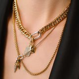 Model wearing the Just Click Tag Necklace Set, a four-piece gold necklace set featuring a Cuban link chain, a box chain, and a rope chain with diamond-like accents, two dog tag charms, and a spike charm.