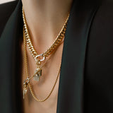 Model wearing the Just Click Tag Necklace Set, a four-piece gold necklace set featuring a Cuban link chain, a box chain, and a rope chain with diamond-like accents, two dog tag charms, and a spike charm.