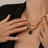 The Letter Necklace Set, which is a three-piece layered necklace set, features a mix of gold and silver chains for a bold and versatile look. It includes a gold square charm engraved with the letter 'X' and a sleek lightning bolt pendant, adding unique detail to the layered design.