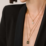 Model wearing the You and the Needle Necklace Set, a three-piece gold necklace set with a needle pendant and initial charm.