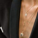 Model wearing the You and the Needle Necklace Set, a three-piece gold necklace set with a needle pendant and initial charm.