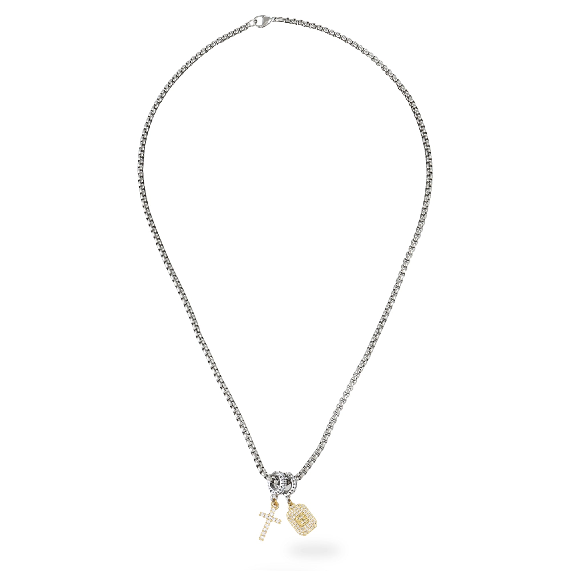 The Double The Charm Necklace, which is a single-piece silver chain necklace, features two gold charms—a sleek cross adorned with small stones and a rectangular tag charm—offering a delicate balance of elegance and symbolism. |||