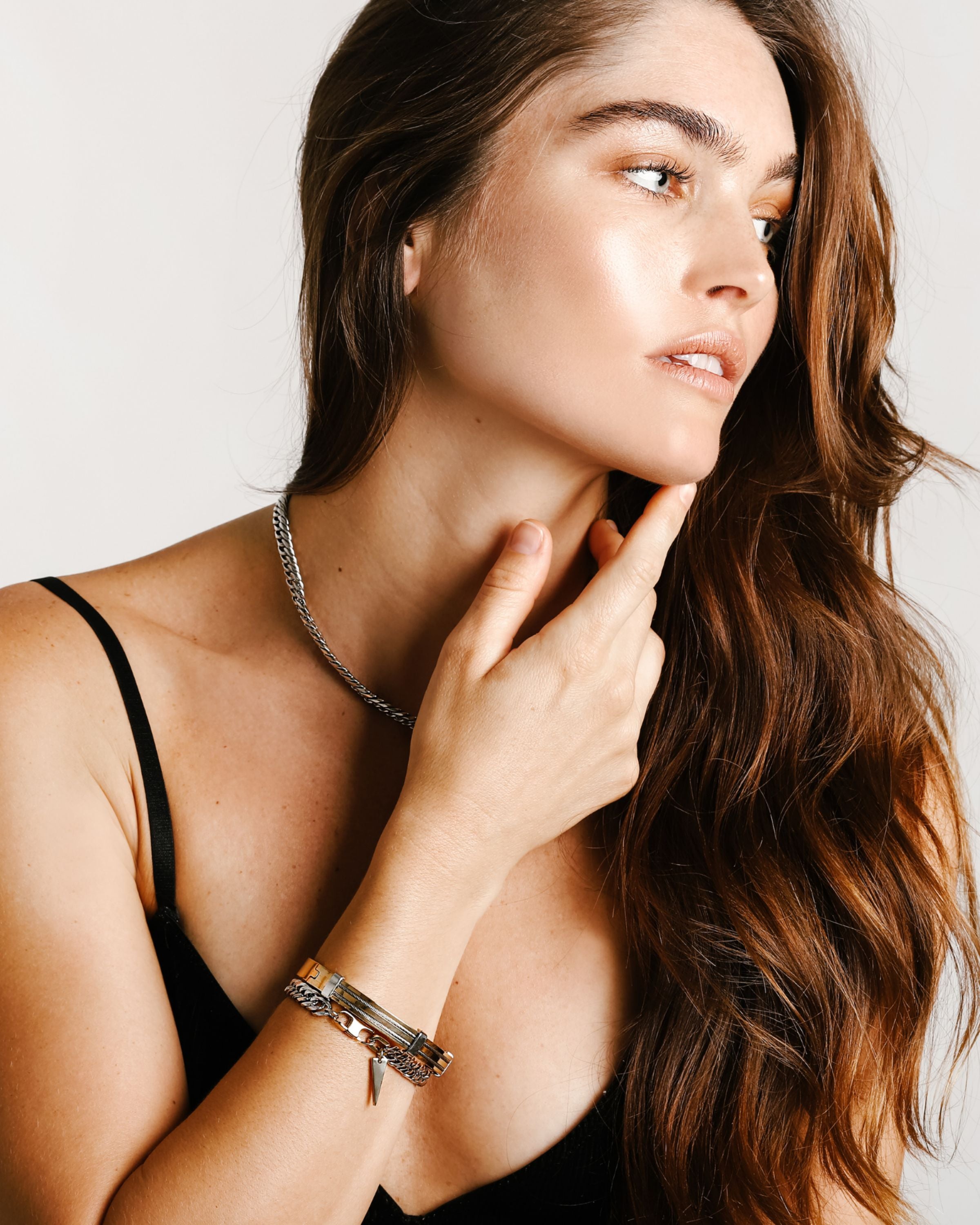 Model wearing a silver chain necklace and the Iron stack which comes with two bracelets. One is the Iron Bracelet which is a 7 inches Stainless steel chain with two gold plated triangle charms and the Marinero Bangle which is a Stainless steel 18K gold plated bangle with silver details.