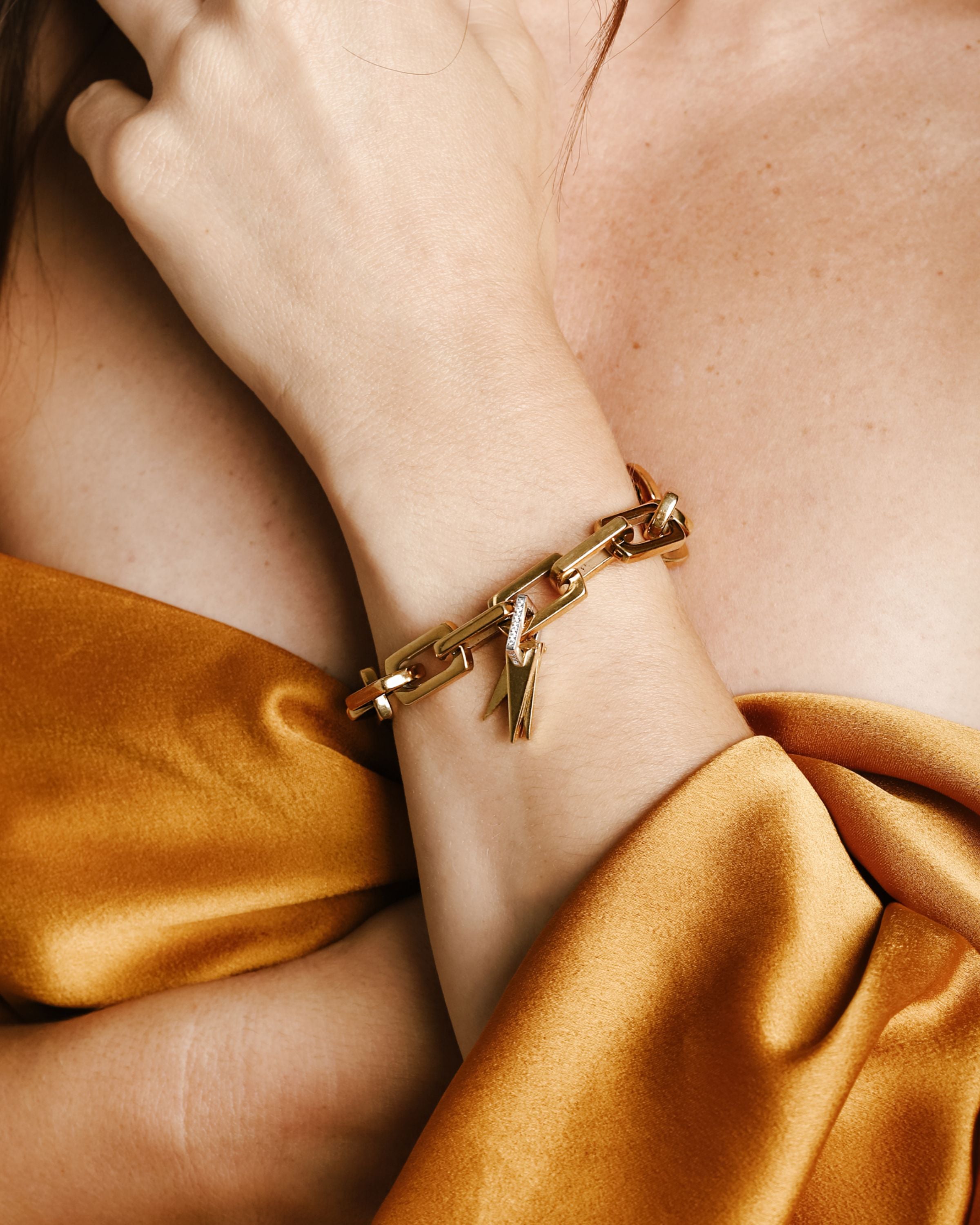 Model wearing the Light Bracelet which is 8 inches in length, Stainless steel 18k gold plated link chain with gold Triangle charms & Zirconia.