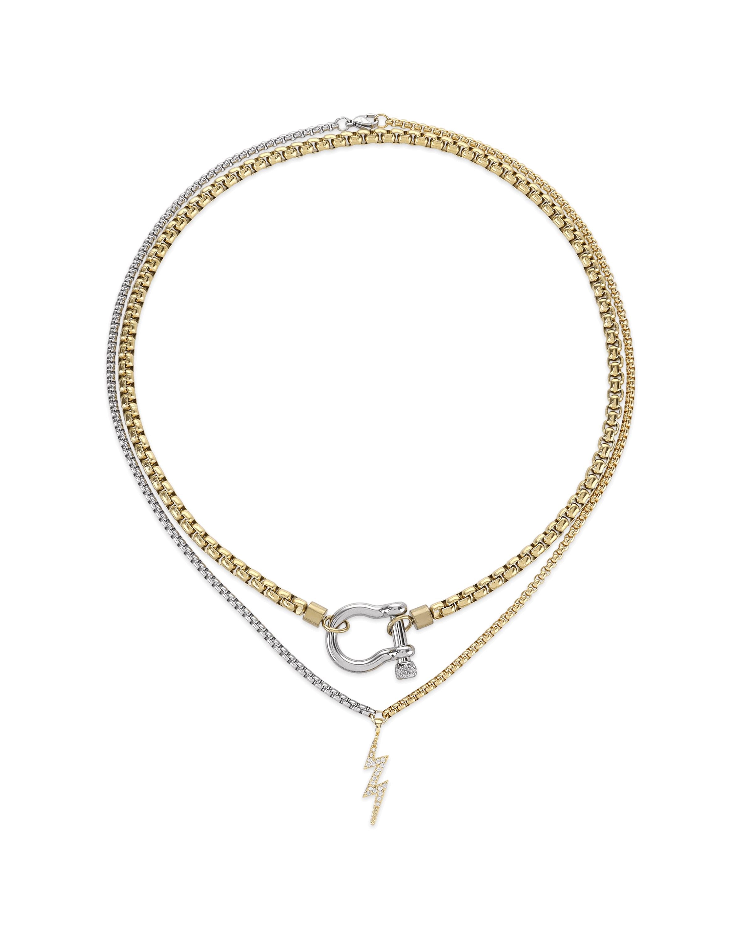 The Herradura Thunder Layered Necklace, a two-piece silver and gold necklace set featuring a box chain and a Cuban chain with a gold horseshoe clasp and a lightning bolt charm accented with diamond-like stones.