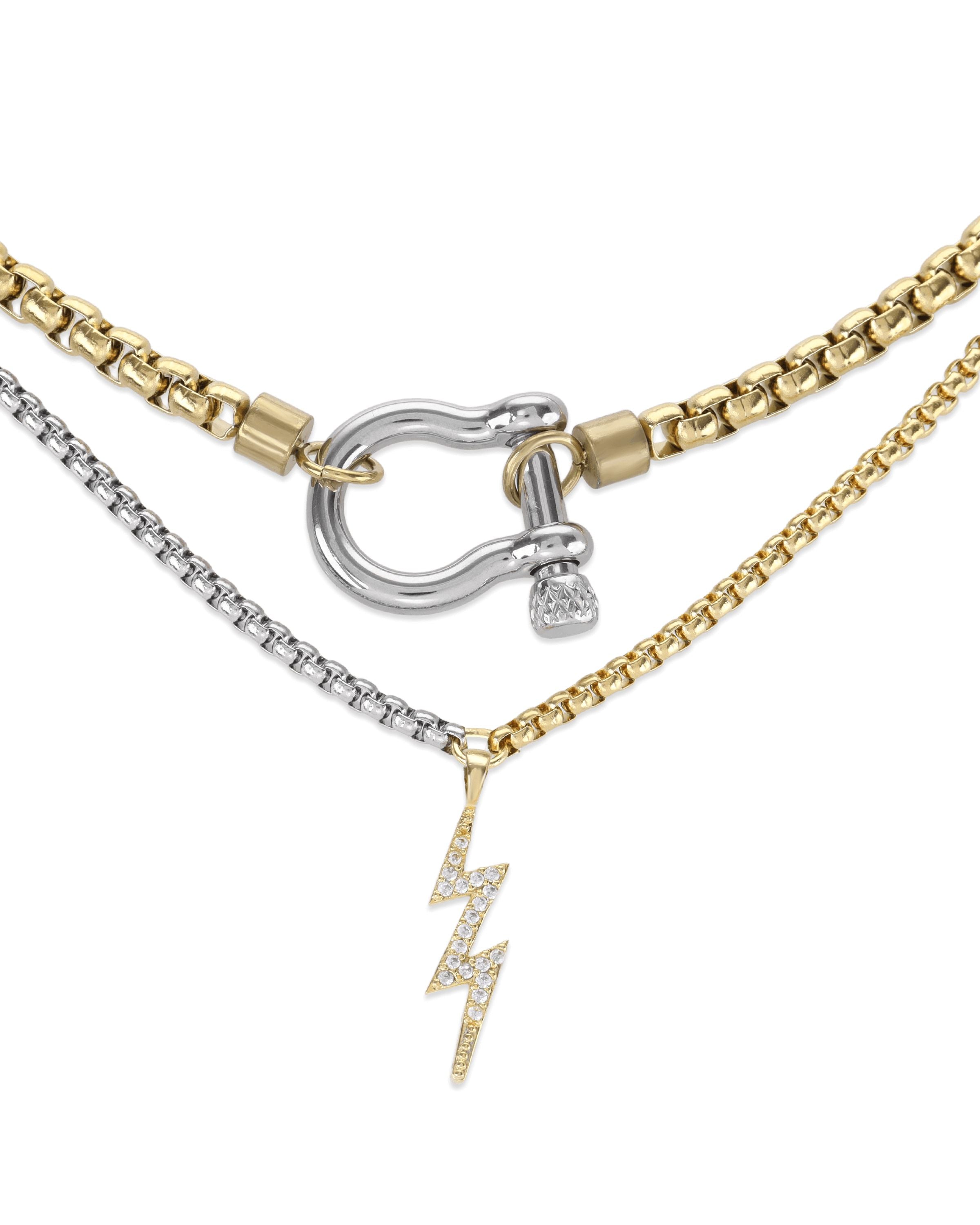 The Herradura Thunder Layered Necklace, a striking mixed-metal piece featuring three layers of gold and silver chains connected by a bold silver clasp. This edgy layered necklace includes a lightning bolt charm, combining elegance with a modern, statement-making design ideal for adding depth and contrast to any outfit.