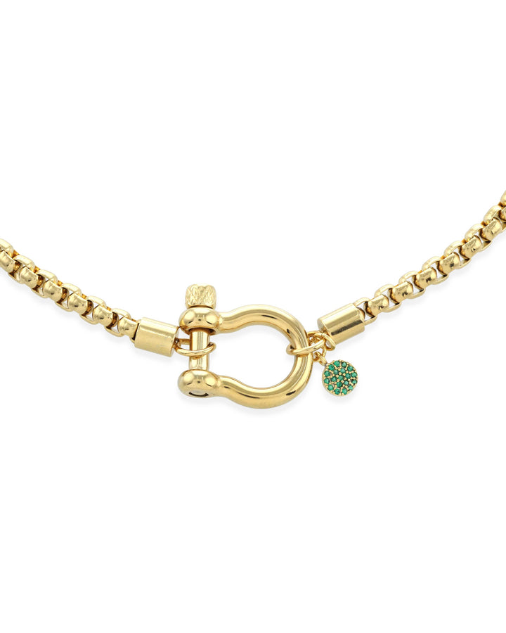The Herradura Green Necklace, a single gold chain necklace featuring a bold clasp and a small green charm. This sleek and modern piece adds a touch of color and elegance, perfect for layering or wearing alone as a statement accessory.