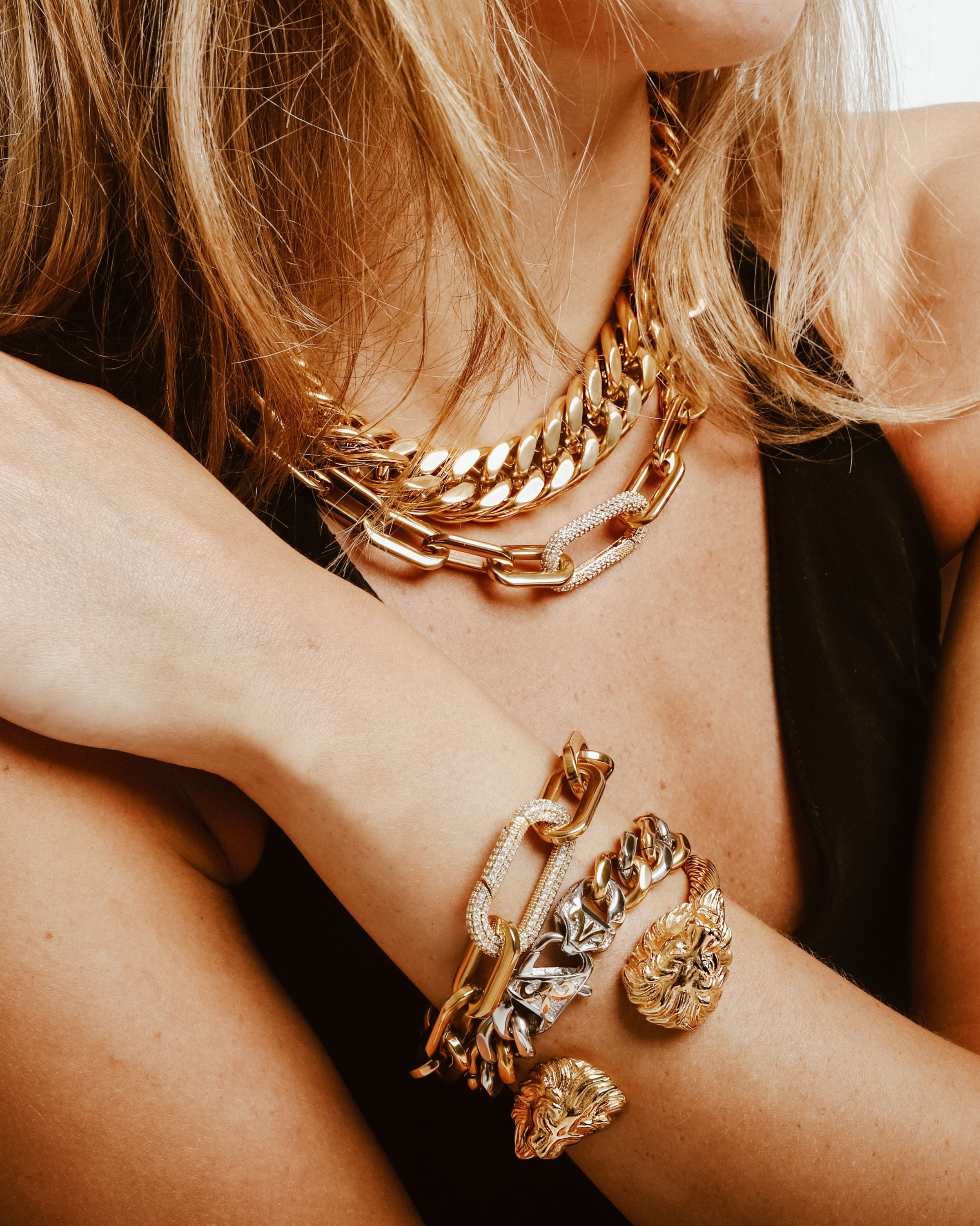 Model wearing the Puerto Fino Bracelet, a gold chain bracelet with a unique elongated link design and a clasp accented with diamond-like stones. She is also wearing the palma and dragon bracelets as well as the palma and puerto fino necklaces.