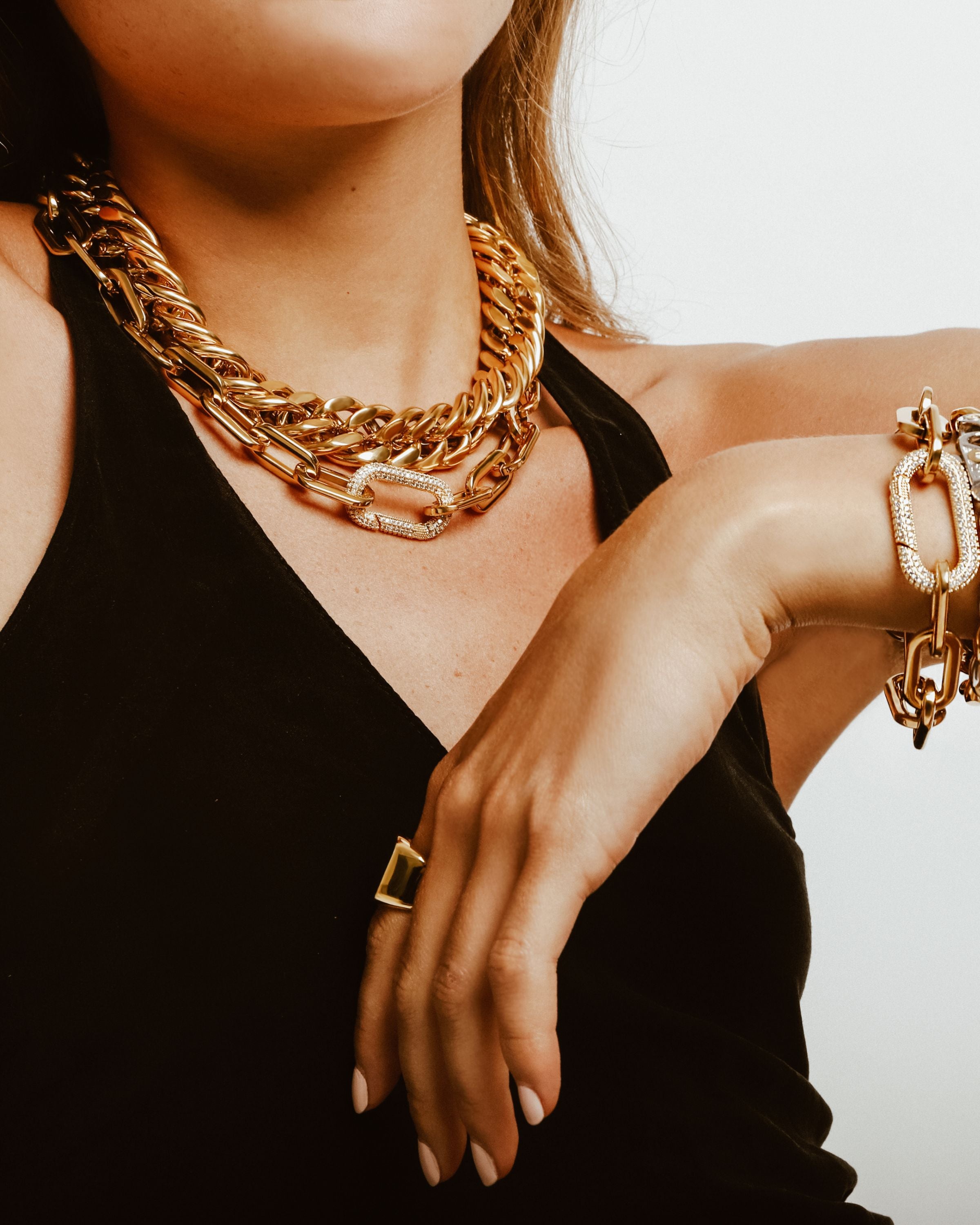 Model wearing a black halter top accessorized with the Puerto Fino Necklace in gold plated stainless steel with a Micro Pave Zirconia lock and the Palma necklace. She is also wearing the Palma bracelet, Puerto Fino Bracelet and the Lion bracelet.