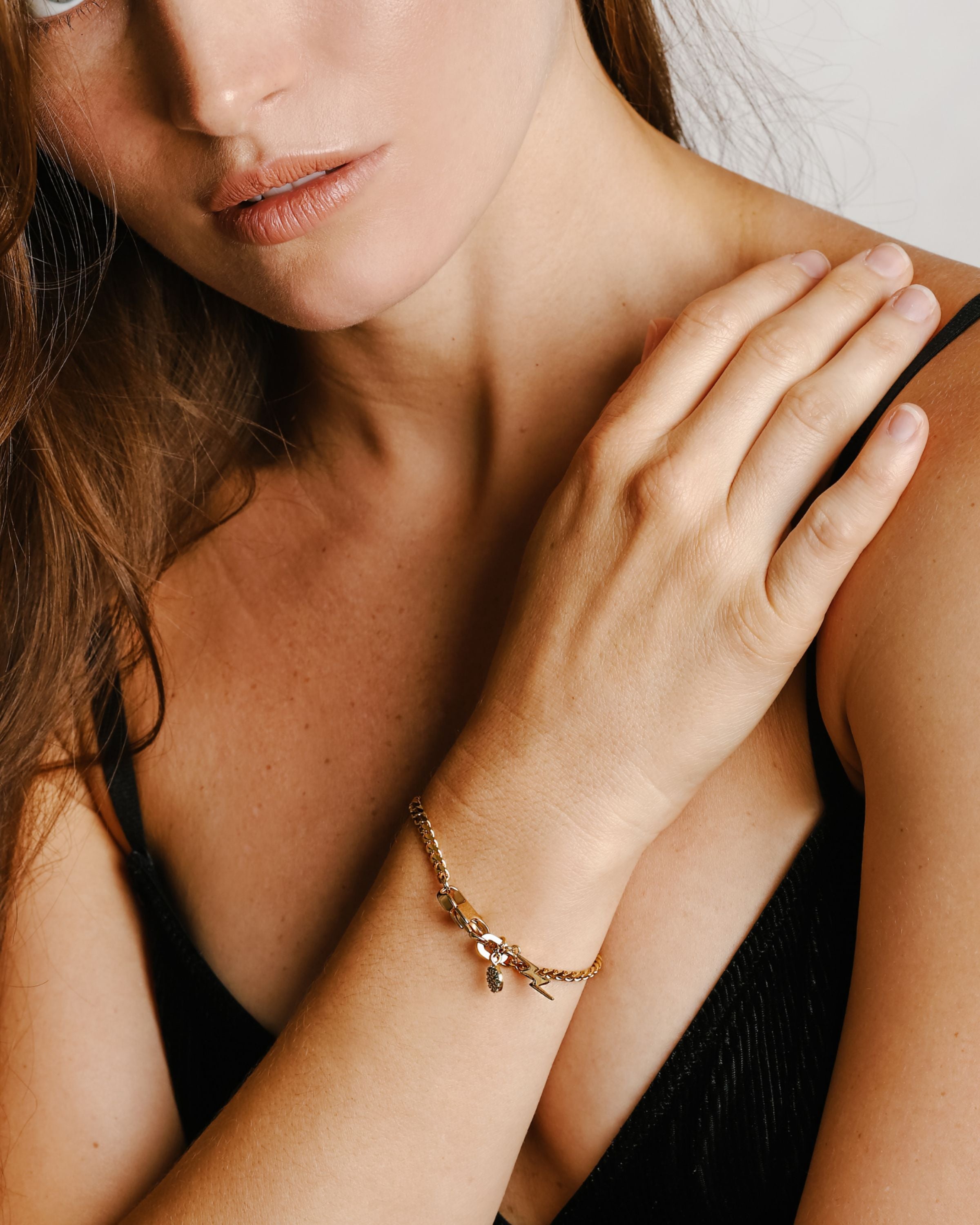 Model is wearing the RISTRETTO BLENDED BRACELET which is a 7" half stainless steel chain and half stainless steel 18k gold plated chain with an 18k gold plated triangular and green zirconia pendant.