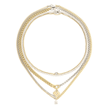 The Mix Tennis Compass Layered Necklace Set, which is a four-piece gold and silver layered necklace set, features bold curb chains, sparkling tennis chains, and a gold compass pendant with a diamond-accented charm.