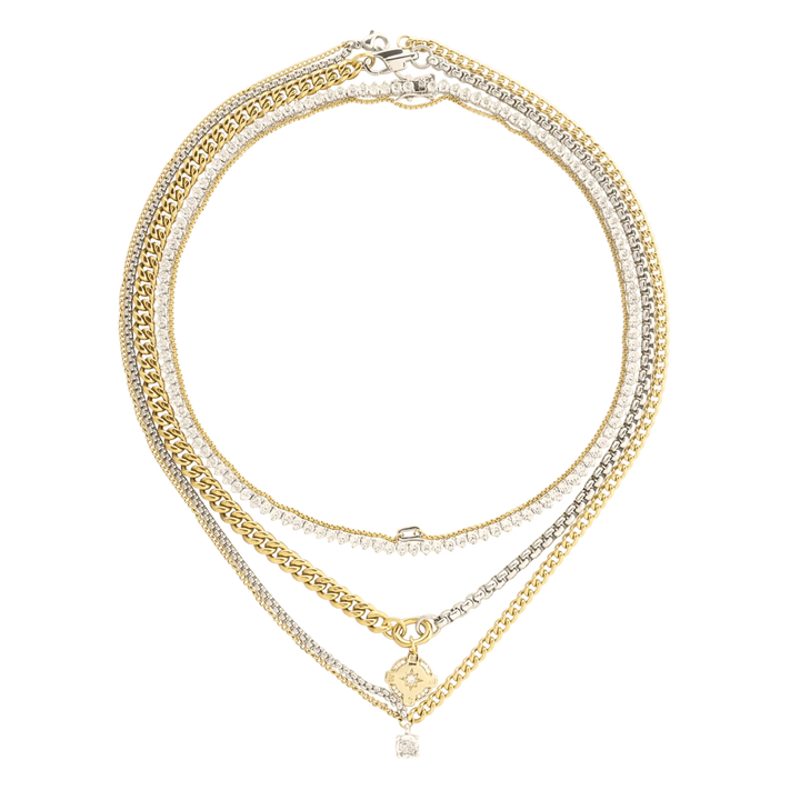The Mix Tennis Compass Layered Necklace Set, which is a four-piece gold and silver layered necklace set, features bold curb chains, sparkling tennis chains, and a gold compass pendant with a diamond-accented charm.