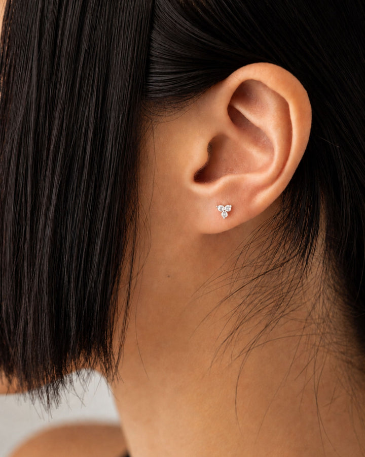 three-gem cluster stud earring styled in a cartilage ear piercing. It features a tri-gem setting