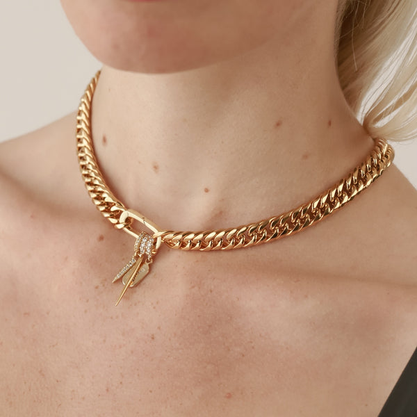 Model wearing the Just Click Letter Chain which is made of 18 k gold plated chunky chain and box clasp with three Just Click charms. The Just Click Needle, Letter and the  JUST CLICK SPIKE CHARM which is made of Sterling silver 18k gold plated encrusted zirconia long spike charm.