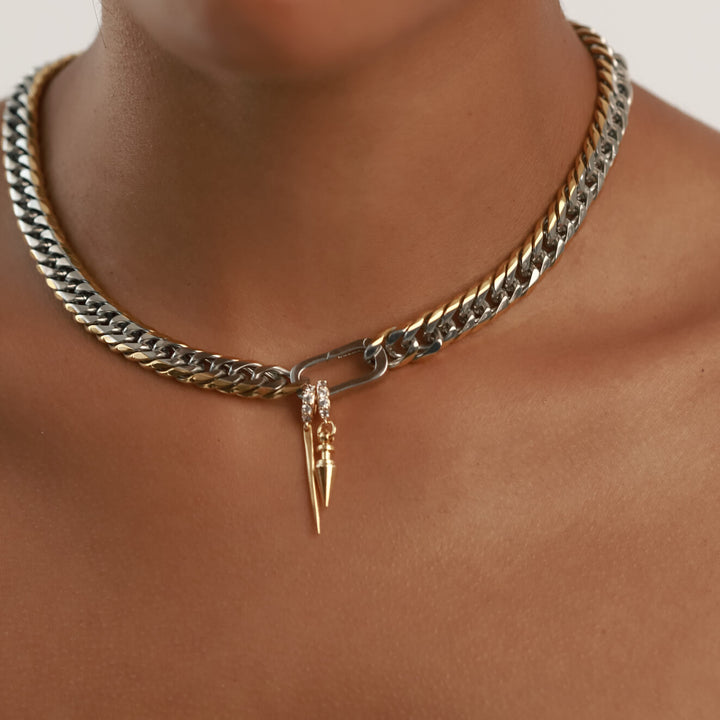 Model wearing the JUST CLICK SPIKE CHAIN made of Mix metal stainless steel and has two charms. The 18k gold plated needle charm and the JUST CLICK ROUND SPIKE CHARM which is made of Sterling silver 18k gold plated spike charm. The link to where the necklace goes is encrusted with zirconia.