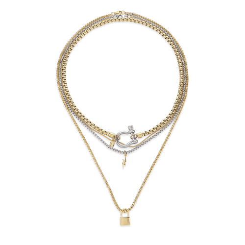 The Herradura Lock Layered Necklace Set, a four-piece silver and gold necklace set featuring a variety of chains with a gold horseshoe clasp, a lightning bolt charm, and a padlock charm.