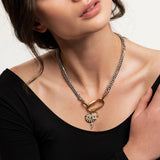 The Anne Charm Necklace, which is a delicate silver chain necklace featuring a multiple charm pendant, worn by a woman in a black top.