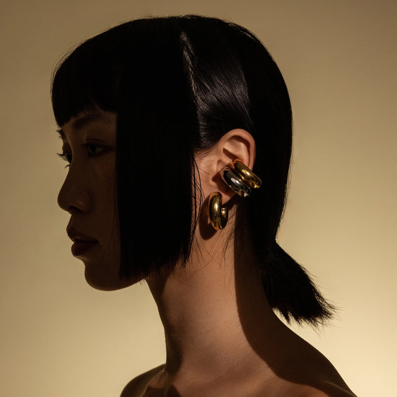 Model wearing three Chunky Bagel Ear Cuff, a gold ear cuff with a thick, rounded design.