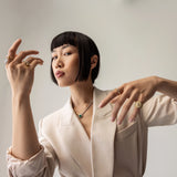 Model wearing the Abuela ring on her left pinky finger. it's a gold textured statement ring with diamond accents in a unique wave design.
