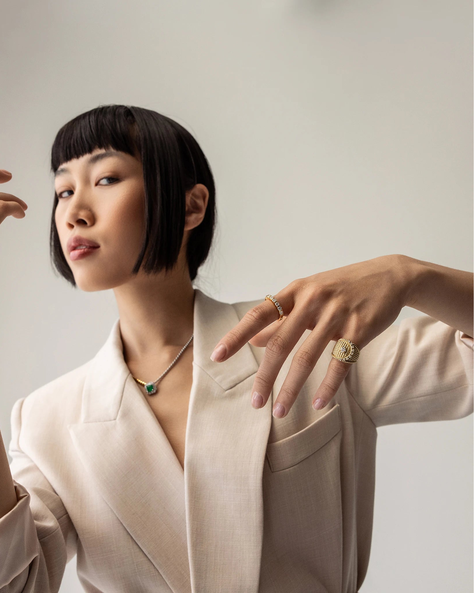 Model wearing the Abuela ring on her left pinky finger. it's a gold textured statement ring with diamond accents in a unique wave design.