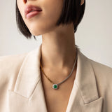 Model wearing the Mixed Emerald Chain, a gold and silver chain featuring a single emerald stone accented with a diamond-like halo.