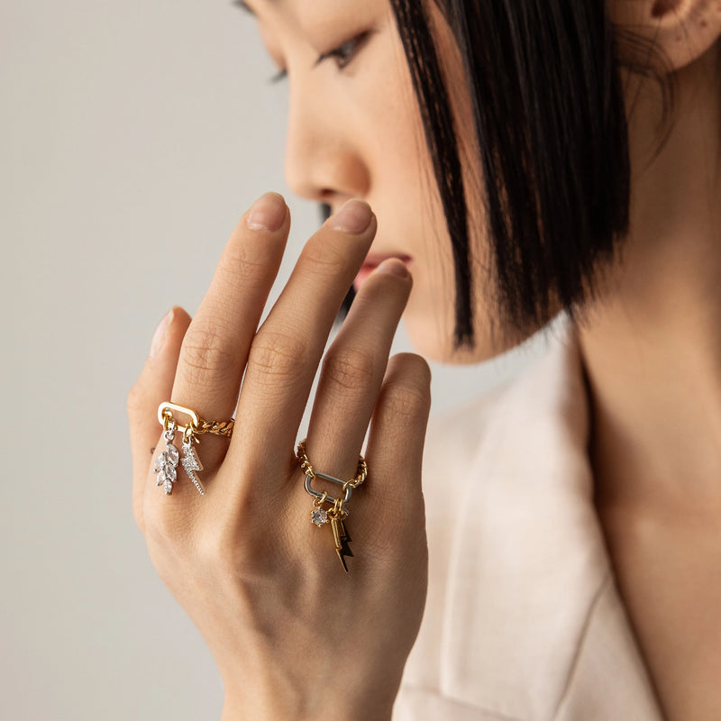 Model wearing the The Electric Leaf Can Opener Ring, a bold and unique statement piece featuring a gold chain with a detachable can opener clasp adorned with sparkling leaf and a lightning bolt charm.