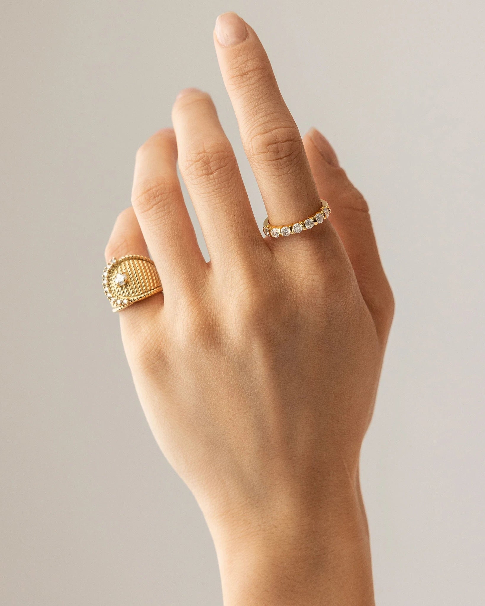 The Abuela Ring worn on the pinky finger which is a Gold textured statement ring with diamond accents in a unique wave design.