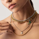 Model wearing the Just Click Emerald Tennis Necklace Set, a four-piece gold and silver necklace set featuring a variety of chains with diamond-like accents, emerald accents, and a variety of charms.
