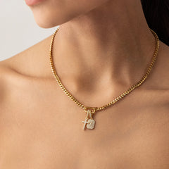 Model wearing a can opener necklace in gold with the Cross Clip On Charm, a gold charm featuring a cross design accented with pave diamonds and the celestial charm. ||| MIX