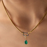Model wearing a gold necklace with can opener clasp with the Emerald Teardrop Clip On Charm, a gold charm featuring a single teardrop-shaped emerald. ||| GOLD