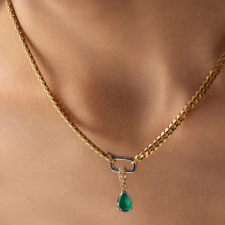 Model wearing a gold necklace with can opener clasp with the Emerald Teardrop Clip On Charm, a gold charm featuring a single teardrop-shaped emerald. ||| GOLD