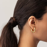 Model wearing the Ringed-Up Bagel Hoops, a stunning pair of gold hoop earrings featuring a distinctive segmented design inspired by the shape of a bagel. 