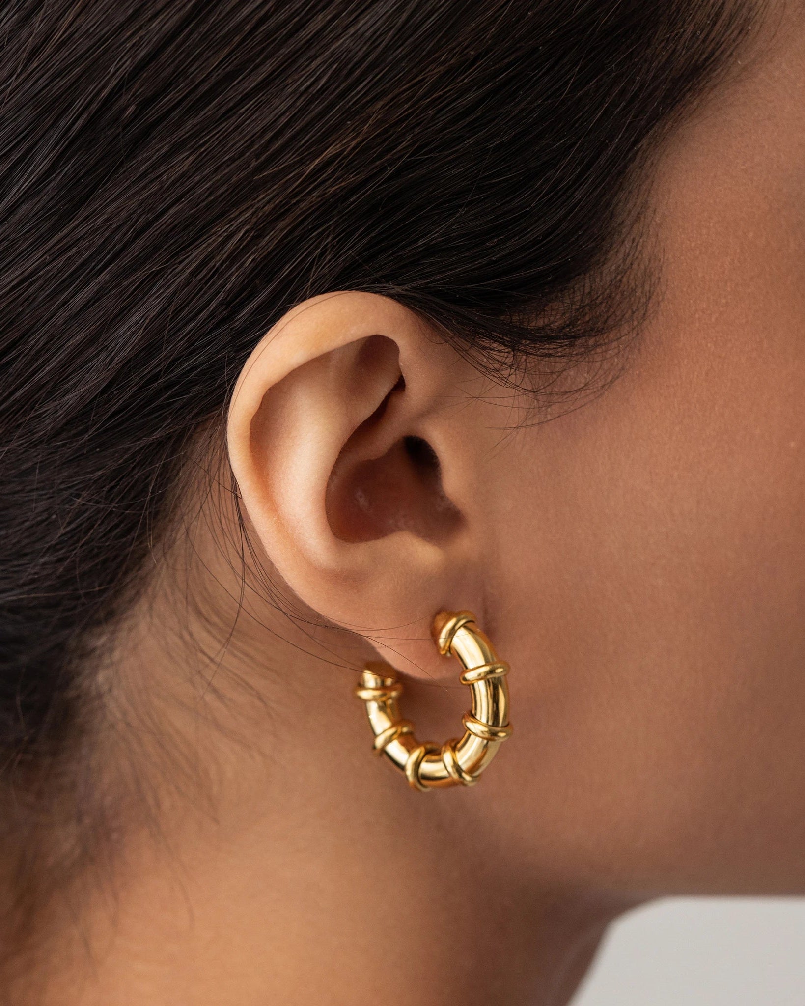 Model wearing the Ringed-Up Bagel Hoops, a stunning pair of gold hoop earrings featuring a distinctive segmented design inspired by the shape of a bagel. 