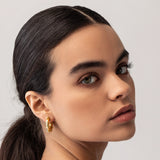 Model wearing the Ringed-Up Bagel Hoops, a stunning pair of gold hoop earrings featuring a distinctive segmented design inspired by the shape of a bagel. 
