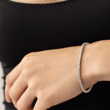 The Sparkling Thin Tennis Bracelet, which is a single silver bracelet featuring a delicate row of shimmering stones, elegantly worn on the wrist, showcasing its timeless and minimalist design ideal for everyday elegance.