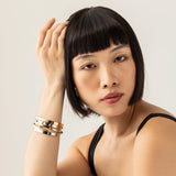 Model wearing the Spiked Armor Bracelet Stack, a four-piece gold and silver bracelet stack featuring bangles with spike accents, diamond-like stones.