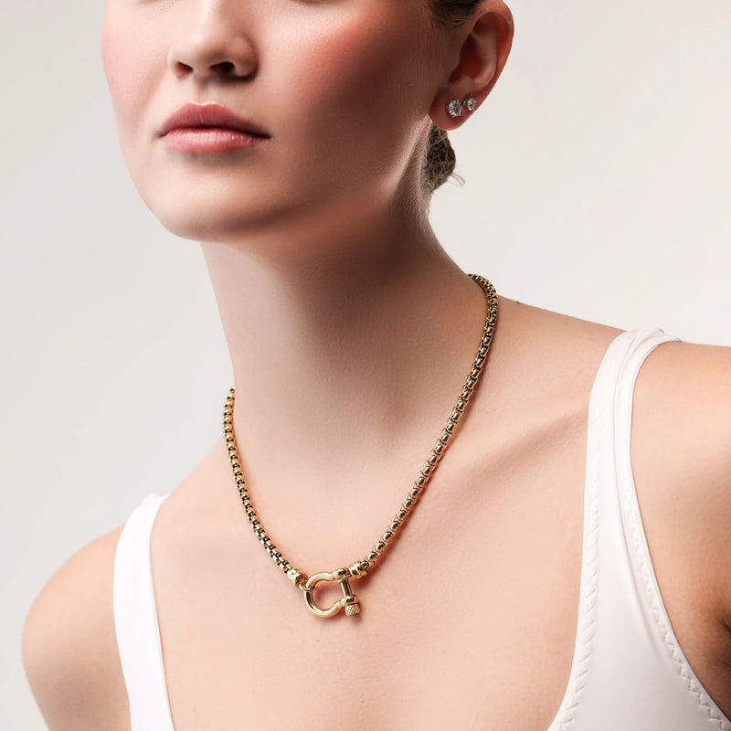 Model wearing the Herradura Signature, a gold necklace featuring a box chain with a gold horseshoe clasp.