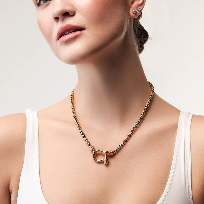 Model wearing the Herradura Signature, a gold necklace featuring a box chain with a gold horseshoe clasp.