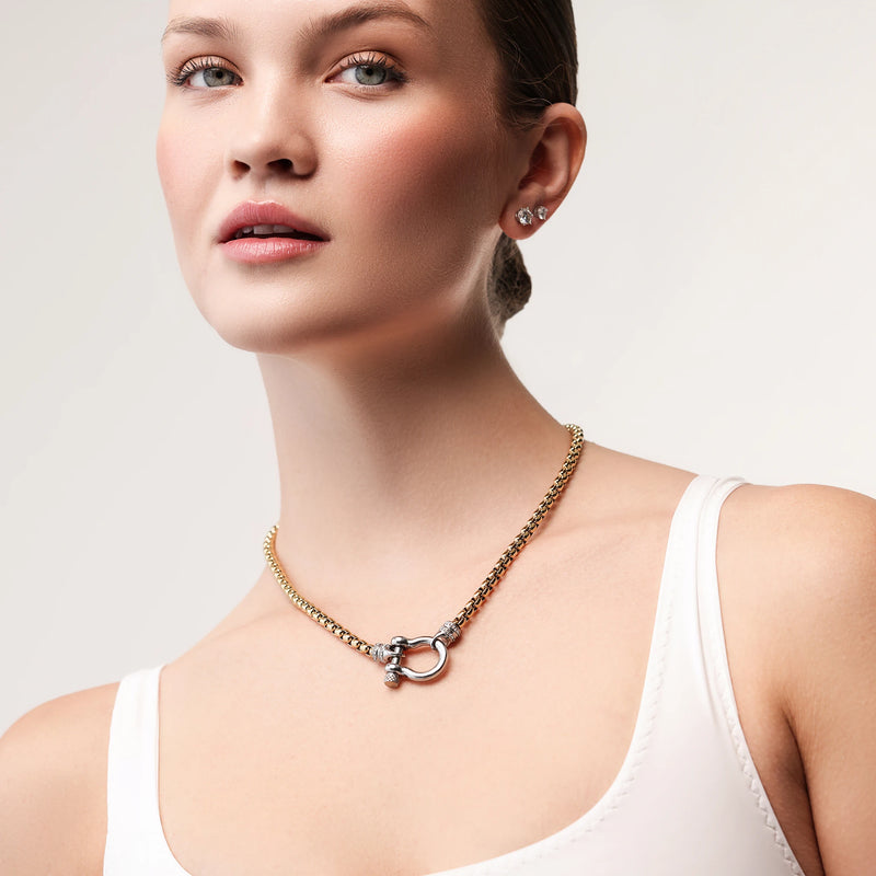 Model wearing the Herradura Signature Pave Mix, a gold necklace featuring a box chain with a silver horseshoe clasp accented with pave-set diamond-like stones.