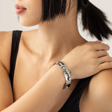 Model wearing the Silver Arrow Bracelet Stack, a three-piece silver bracelet stack featuring two bangles with spike accents and and a diamond-like tennis bracelet.