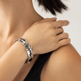 Model wearing the Silver Arrow Bracelet Stack, a three-piece silver bracelet stack featuring two bangles with spike accents and and a diamond-like tennis bracelet.